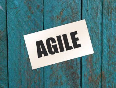 Kağıt kartvizitte AGILE yazılı, ahşap arka planda yakın plan. İş Konsepti
