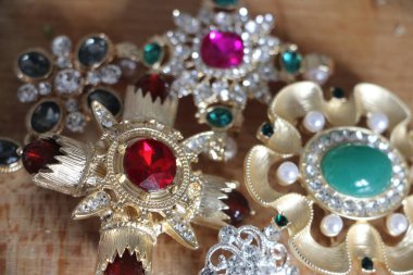 Zümrüt değerli taşlı klasik broşürler. Farklı renklerde cam ve metal broşlar. Renkli ve moda broşları. Lüks bir geçmişi var. Seçici odak