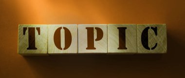 Kırmızı arkaplanda tahta bloklu TOPIC kavramı.