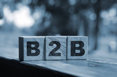 Tahta küplerdeki B2C harfleri dışarıda duran ahşap masaya konmuş. Yaz doğası geçmişi. Ticaretten müşteriye konsept. İstemci odaklı.