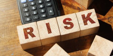 Tahta küplere ve hesap makinesine yazılan RISK kelimesi. Mali risk değerlendirmesi, risk ödülü ve portföy risk yönetimi iş konsepti.