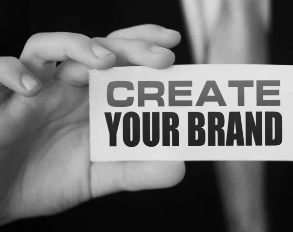 Create Your Brand message on white card in hand of businessman. New business startup concept.