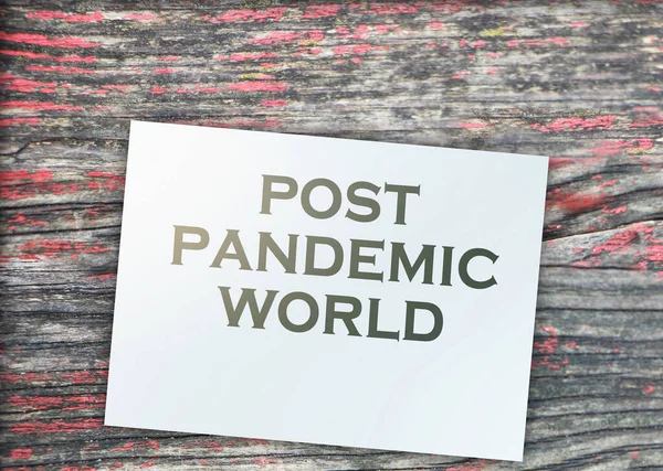 Post-pandemic world text on page and paper dollar signs around on beautiful wooden background. Healthcare quarantine Concept.