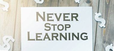 Metin, sayfa ve kağıt para işaretlerini ahşap masada öğrenmeyi asla bırakmaz. Ömür boyu eğitim kavramı