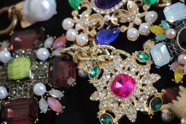 Zümrüt değerli taşlı klasik broşürler. Farklı renklerde cam ve metal broşlar. Renkli ve moda broşları. Lüks bir geçmişi var. Seçici odak