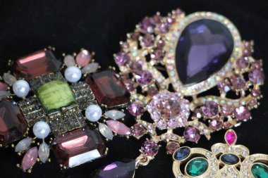 Zümrüt değerli taşlı klasik broşürler. Farklı renklerde cam ve metal broşlar. Renkli ve moda broşları. Lüks bir geçmişi var. Seçici odak
