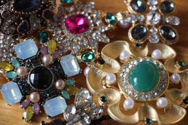 Zümrüt değerli taşlı klasik broşürler. Farklı renklerde cam ve metal broşlar. Renkli ve moda broşları. Lüks bir geçmişi var. Seçici odak