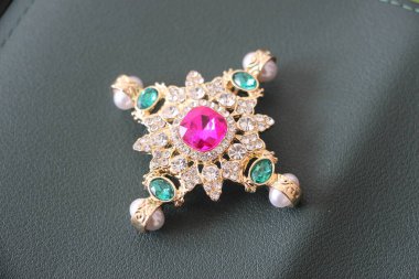 Zümrüt değerli taşlı klasik broşürler. Farklı renklerde cam ve metal broşlar. Renkli ve moda broşları. Lüks bir geçmişi var. Seçici odak