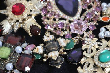 Zümrüt değerli taşlı klasik broşürler. Farklı renklerde cam ve metal broşlar. Renkli ve moda broşları. Lüks bir geçmişi var. Seçici odak