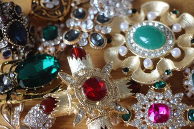 Zümrüt değerli taşlı klasik broşürler. Farklı renklerde cam ve metal broşlar. Renkli ve moda broşları. Lüks bir geçmişi var. Seçici odak