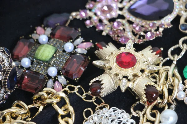 Zümrüt değerli taşlı klasik broşürler. Farklı renklerde cam ve metal broşlar. Renkli ve moda broşları. Lüks bir geçmişi var. Seçici odak