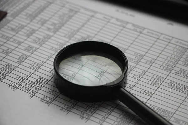 비즈니스 분석가는 확대경을 사용하여 보고서 수치를 — 스톡 사진