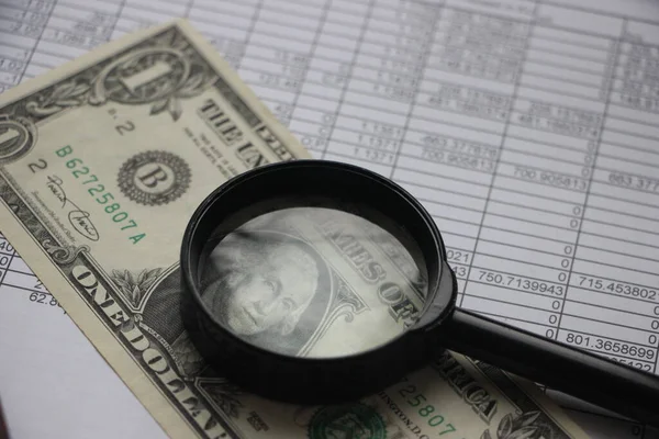 Magnifying glass, financial reports statistics, one dollar bill. Finance and statistic concept.