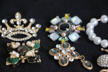 Zümrüt değerli taşlı klasik broşürler. Farklı renklerde cam ve metal broşlar. Renkli ve moda broşları. Lüks bir geçmişi var. Seçici odak