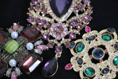 Zümrüt değerli taşlı klasik broşürler. Farklı renklerde cam ve metal broşlar. Renkli ve moda broşları. Lüks bir geçmişi var. Seçici odak