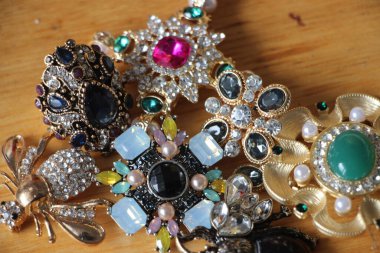 Zümrüt değerli taşlı klasik broşürler. Farklı renklerde cam ve metal broşlar. Renkli ve moda broşları. Lüks bir geçmişi var. Seçici odak