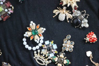 Zümrüt değerli taşlı klasik broşürler. Farklı renklerde cam ve metal broşlar. Renkli ve moda broşları. Lüks bir geçmişi var. Seçici odak