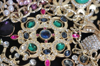 Zümrüt değerli taşlı klasik broşürler. Farklı renklerde cam ve metal broşlar. Renkli ve moda broşları. Lüks bir geçmişi var. Seçici odak