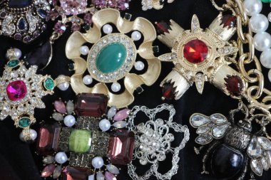 Zümrüt değerli taşlı klasik broşürler. Farklı renklerde cam ve metal broşlar. Renkli ve moda broşları. Lüks bir geçmişi var. Seçici odak