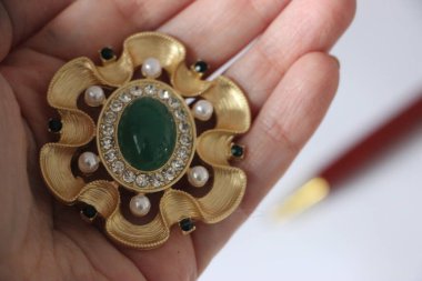 Zümrüt değerli taşlı klasik broşürler. Farklı renklerde cam ve metal broşlar. Renkli ve moda broşları. Lüks bir geçmişi var. Seçici odak