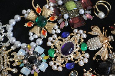 Zümrüt değerli taşlı klasik broşürler. Farklı renklerde cam ve metal broşlar. Renkli ve moda broşları. Lüks bir geçmişi var. Seçici odak