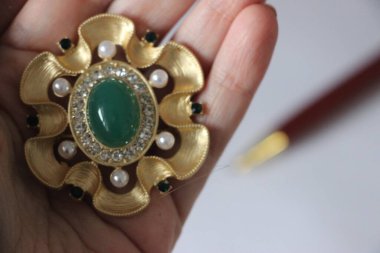 Zümrüt değerli taşlı klasik broşürler. Farklı renklerde cam ve metal broşlar. Renkli ve moda broşları. Lüks bir geçmişi var. Seçici odak