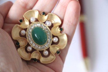 Zümrüt değerli taşlı klasik broşürler. Farklı renklerde cam ve metal broşlar. Renkli ve moda broşları. Lüks bir geçmişi var. Seçici odak