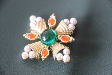 Zümrüt değerli taşlı klasik broşürler. Farklı renklerde cam ve metal broşlar. Renkli ve moda broşları. Lüks bir geçmişi var. Seçici odak