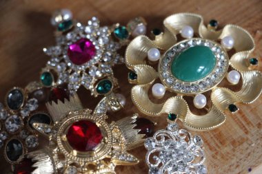 Zümrüt değerli taşlı klasik broşürler. Farklı renklerde cam ve metal broşlar. Renkli ve moda broşları. Lüks bir geçmişi var. Seçici odak