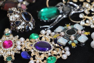 Zümrüt değerli taşlı klasik broşürler. Farklı renklerde cam ve metal broşlar. Renkli ve moda broşları. Lüks bir geçmişi var. Seçici odak