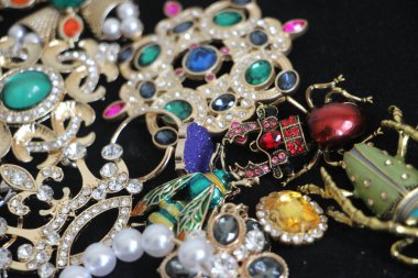 Zümrüt değerli taşlı klasik broşürler. Farklı renklerde cam ve metal broşlar. Renkli ve moda broşları. Lüks bir geçmişi var. Seçici odak