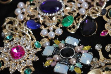 Zümrüt değerli taşlı klasik broşürler. Farklı renklerde cam ve metal broşlar. Renkli ve moda broşları. Lüks bir geçmişi var. Seçici odak