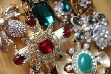 Zümrüt değerli taşlı klasik broşürler. Farklı renklerde cam ve metal broşlar. Renkli ve moda broşları. Lüks bir geçmişi var. Seçici odak