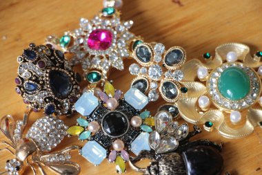 Zümrüt değerli taşlı klasik broşürler. Farklı renklerde cam ve metal broşlar. Renkli ve moda broşları. Lüks bir geçmişi var. Seçici odak