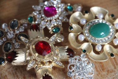 Zümrüt değerli taşlı klasik broşürler. Farklı renklerde cam ve metal broşlar. Renkli ve moda broşları. Lüks bir geçmişi var. Seçici odak