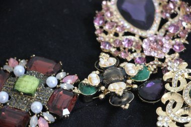 Zümrüt değerli taşlı klasik broşürler. Farklı renklerde cam ve metal broşlar. Renkli ve moda broşları. Lüks bir geçmişi var. Seçici odak