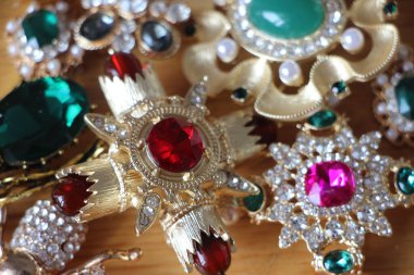 Zümrüt değerli taşlı klasik broşürler. Farklı renklerde cam ve metal broşlar. Renkli ve moda broşları. Lüks bir geçmişi var. Seçici odak