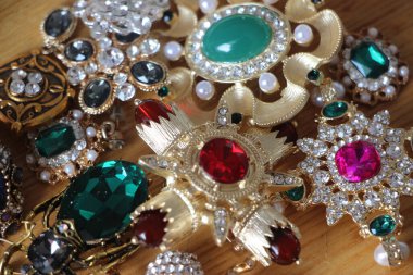 Zümrüt değerli taşlı klasik broşürler. Farklı renklerde cam ve metal broşlar. Renkli ve moda broşları. Lüks bir geçmişi var. Seçici odak