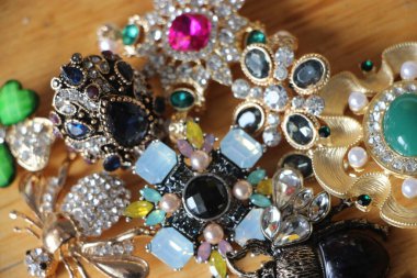 Zümrüt değerli taşlı klasik broşürler. Farklı renklerde cam ve metal broşlar. Renkli ve moda broşları. Lüks bir geçmişi var. Seçici odak