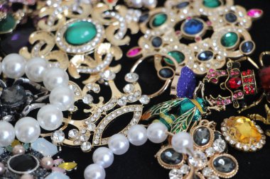 Zümrüt değerli taşlı klasik broşürler. Farklı renklerde cam ve metal broşlar. Renkli ve moda broşları. Lüks bir geçmişi var. Seçici odak