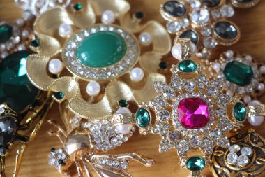 Zümrüt değerli taşlı klasik broşürler. Farklı renklerde cam ve metal broşlar. Renkli ve moda broşları. Lüks bir geçmişi var. Seçici odak