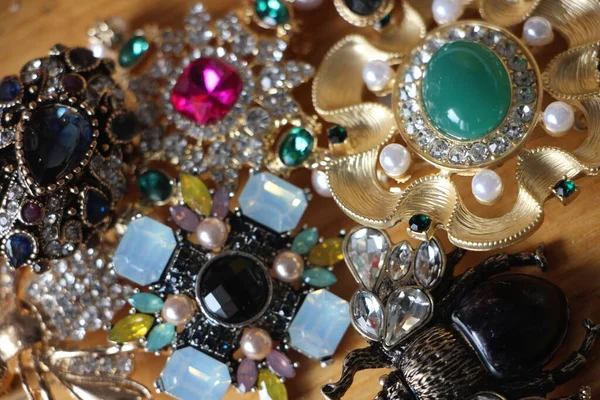 Zümrüt değerli taşlı klasik broşürler. Farklı renklerde cam ve metal broşlar. Renkli ve moda broşları. Lüks bir geçmişi var. Seçici odak