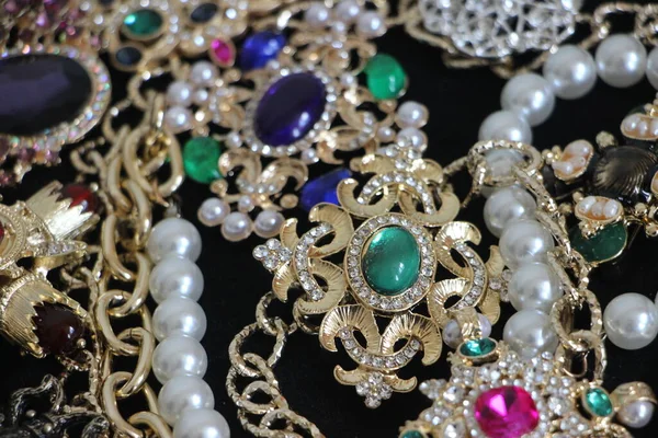 Zümrüt değerli taşlı klasik broşürler. Farklı renklerde cam ve metal broşlar. Renkli ve moda broşları. Lüks bir geçmişi var. Seçici odak