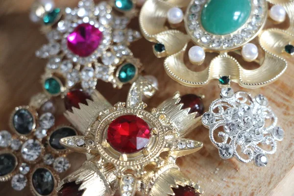 Zümrüt değerli taşlı klasik broşürler. Farklı renklerde cam ve metal broşlar. Renkli ve moda broşları. Lüks bir geçmişi var. Seçici odak