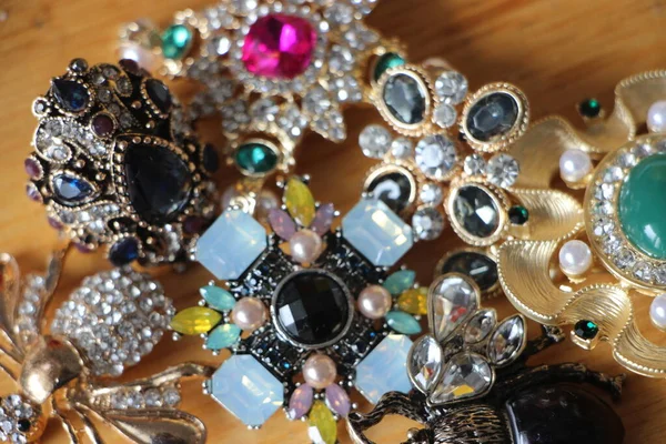 Zümrüt değerli taşlı klasik broşürler. Farklı renklerde cam ve metal broşlar. Renkli ve moda broşları. Lüks bir geçmişi var. Seçici odak