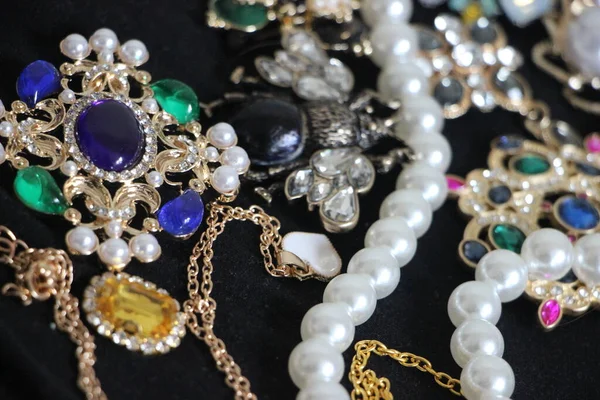 Zümrüt değerli taşlı klasik broşürler. Farklı renklerde cam ve metal broşlar. Renkli ve moda broşları. Lüks bir geçmişi var. Seçici odak