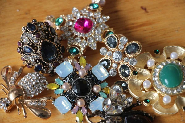 Zümrüt değerli taşlı klasik broşürler. Farklı renklerde cam ve metal broşlar. Renkli ve moda broşları. Lüks bir geçmişi var. Seçici odak