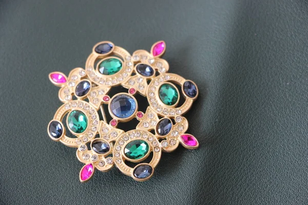 Zümrüt değerli taşlı klasik broşürler. Farklı renklerde cam ve metal broşlar. Renkli ve moda broşları. Lüks bir geçmişi var. Seçici odak
