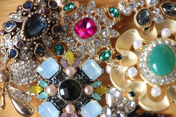 Zümrüt değerli taşlı klasik broşürler. Farklı renklerde cam ve metal broşlar. Renkli ve moda broşları. Lüks bir geçmişi var. Seçici odak