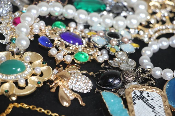 Zümrüt değerli taşlı klasik broşürler. Farklı renklerde cam ve metal broşlar. Renkli ve moda broşları. Lüks bir geçmişi var. Seçici odak